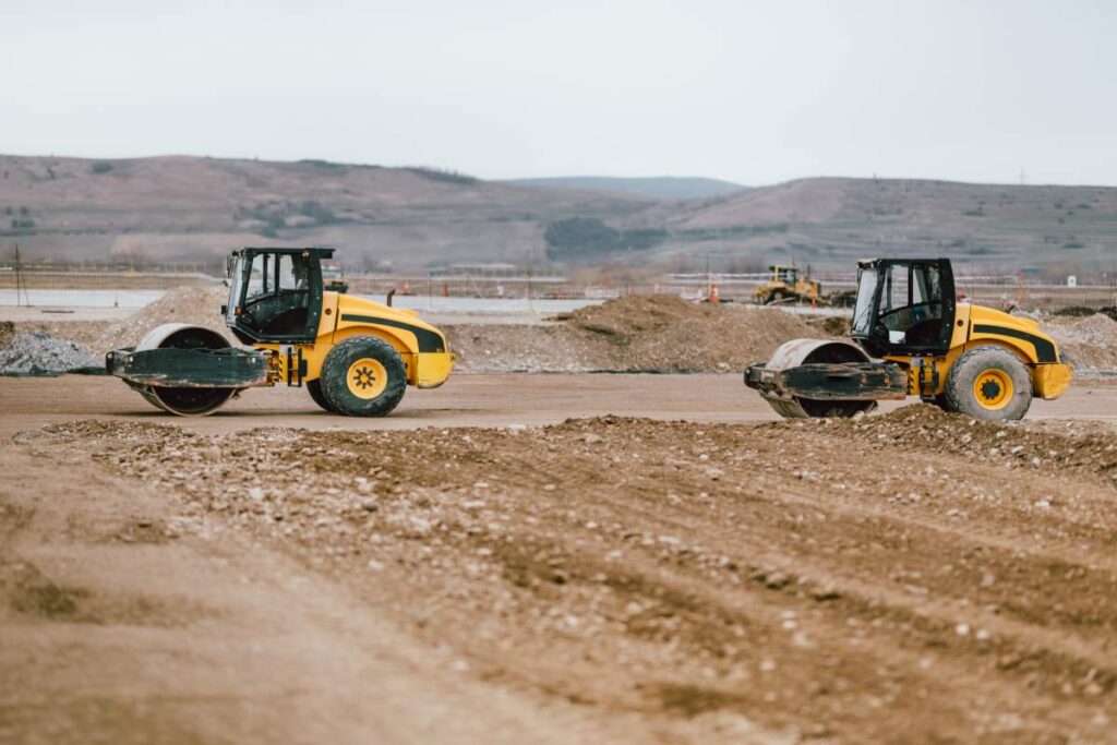 Two Vibratory Soil Compactors during road and highway construction. Industrial roadworks with heavy-duty machinery in construction site