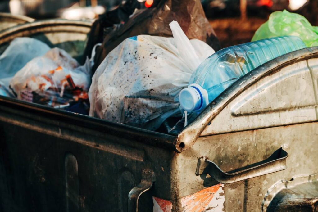 Trash and garbage in metallic dumpster on the street, selective focus