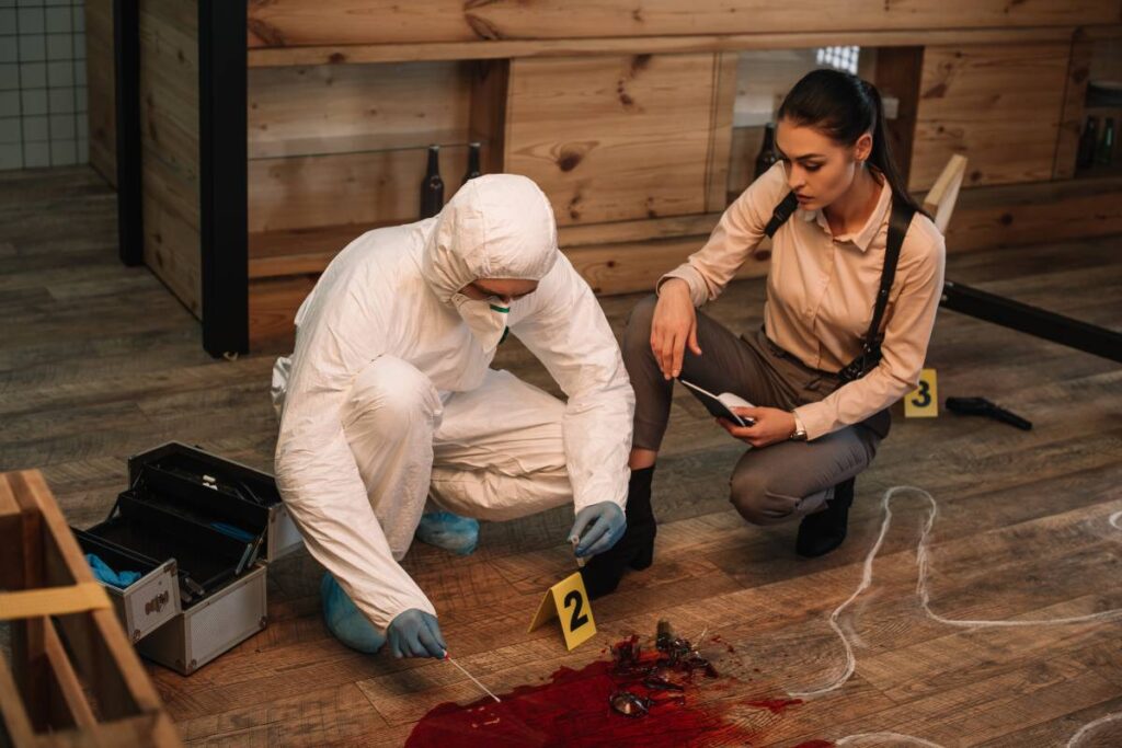 forensic investigator and female detective taking notes and examining crime scene together