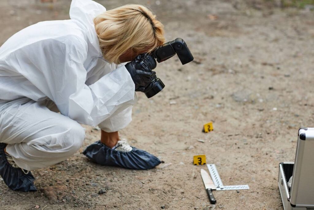 Side view portrait of woman working as crime scene photographer taking photos of evidence outdoors, copy space